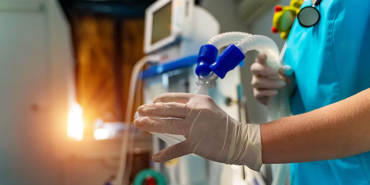 Healthcare worker with medical gloves using a ventilator in a hospital setting