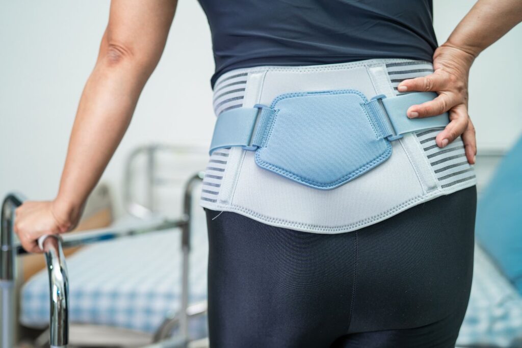 Light blue and gray back support belt for home care, worn by person using walker in medical setting