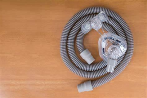 CPAP mask with flexible tubing for respiratory therapy on a wooden surface