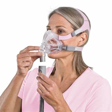 Woman wearing a CPAP mask adjusting tubing, home respiratory care medical supply