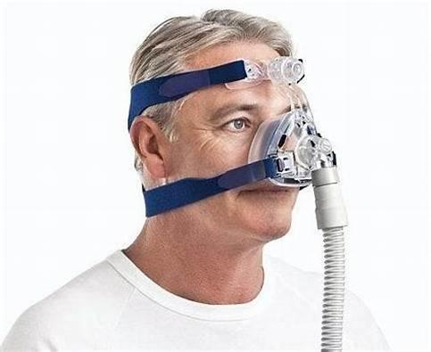 Man wearing CPAP nasal mask with headgear and breathing tube for sleep apnea therapy
