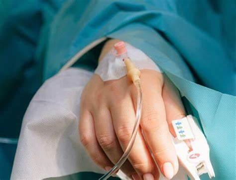 Patient hand with IV catheter and medical tubing, hospital setting, home care supplies