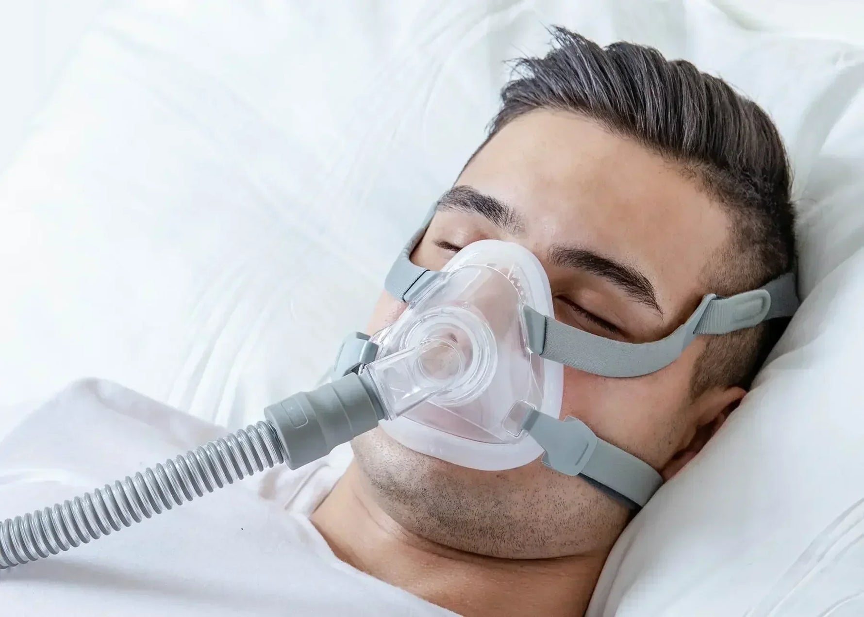 Man sleeping while wearing full face CPAP mask for sleep apnea therapy
