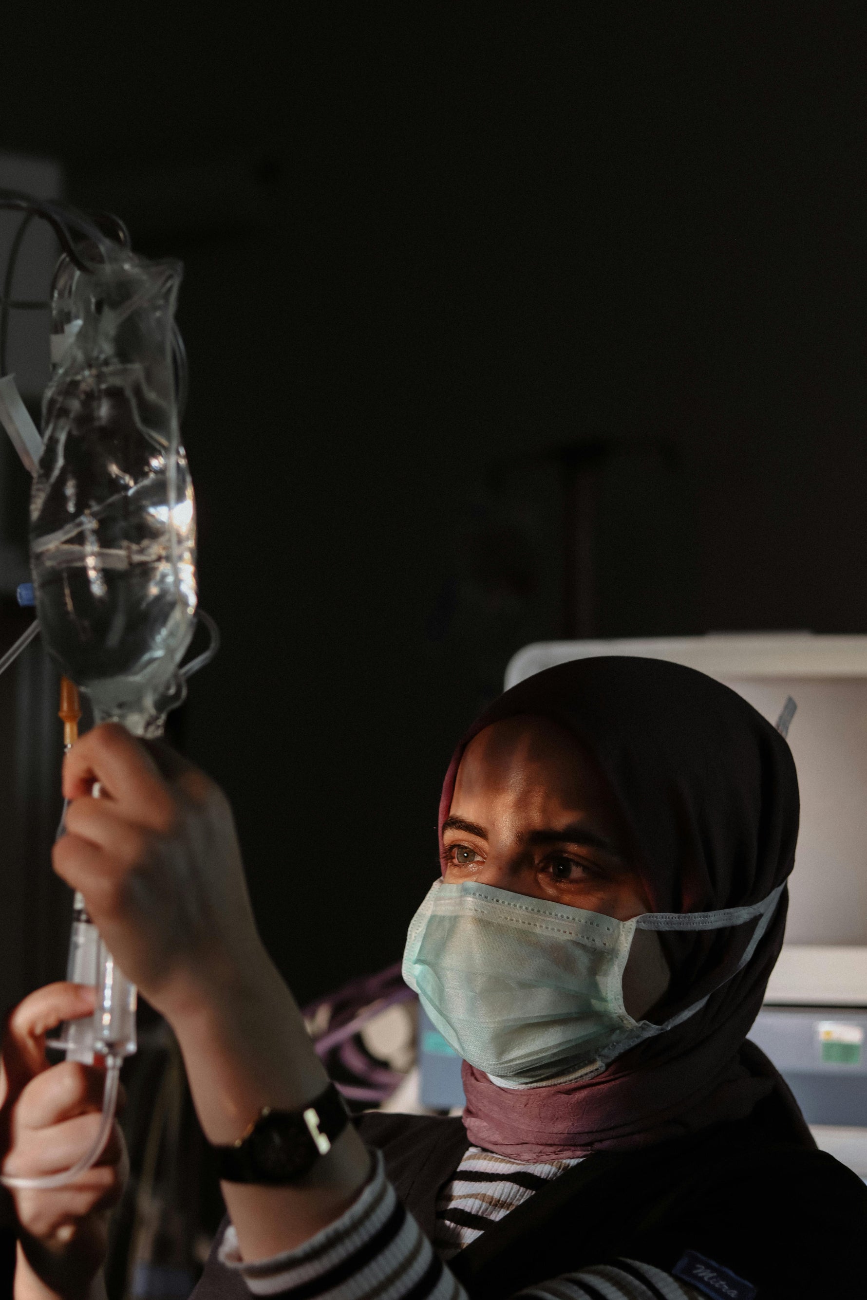 Healthcare worker adjusting IV bag with medical supplies in clinical setting