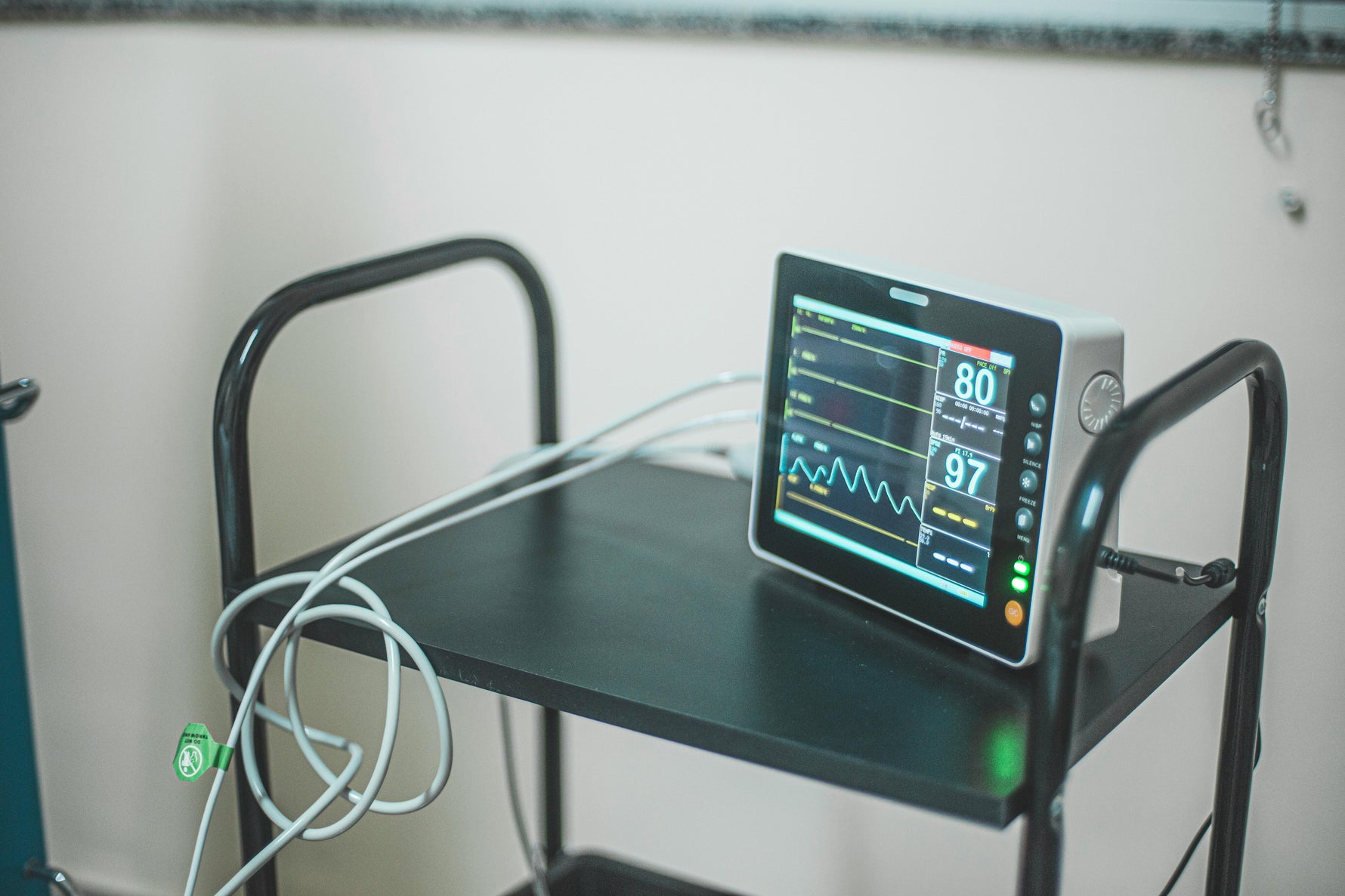 Medical patient monitor displaying vital signs on cart for home care or clinical use