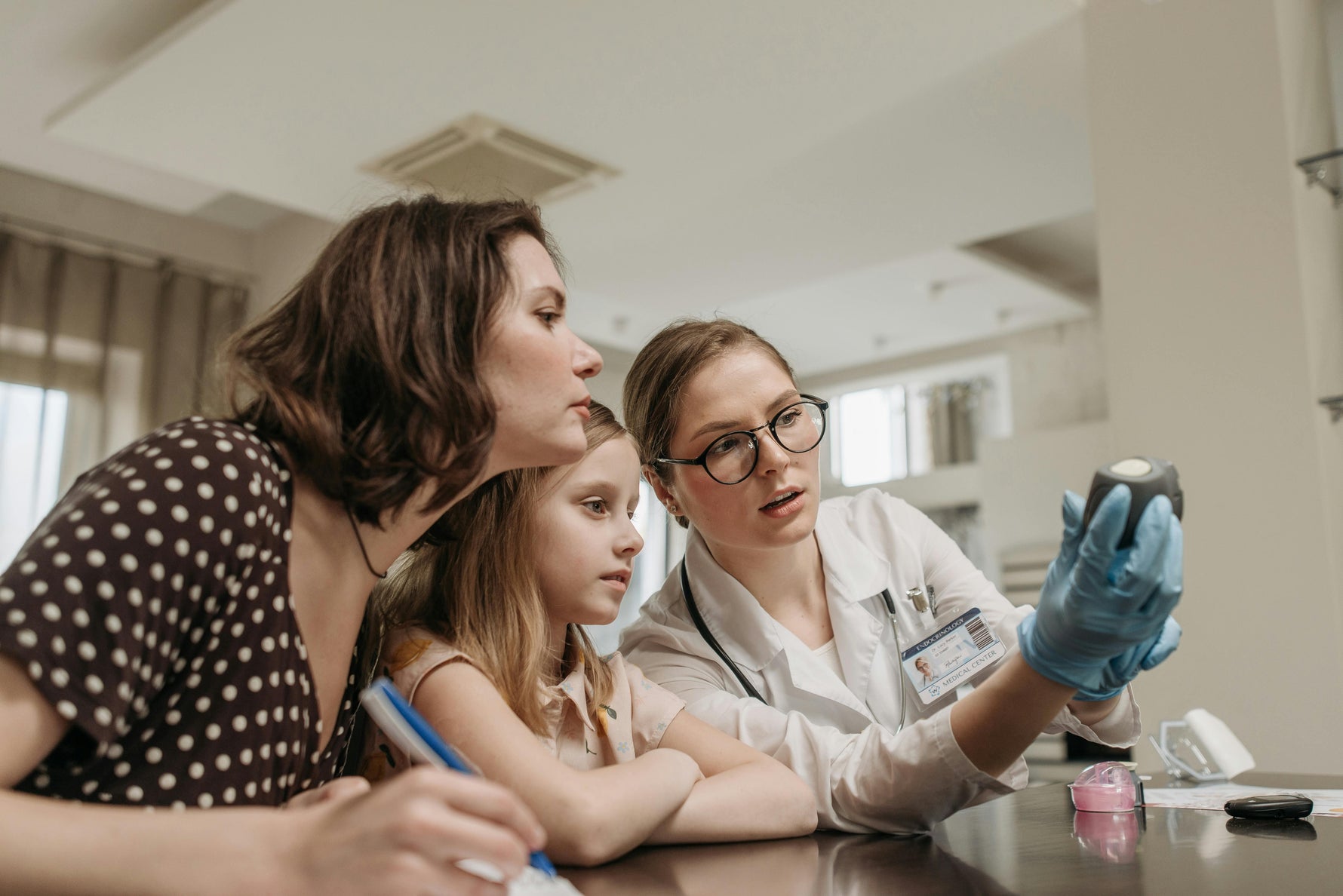 Female doctor showing medical device to woman and child during consultation