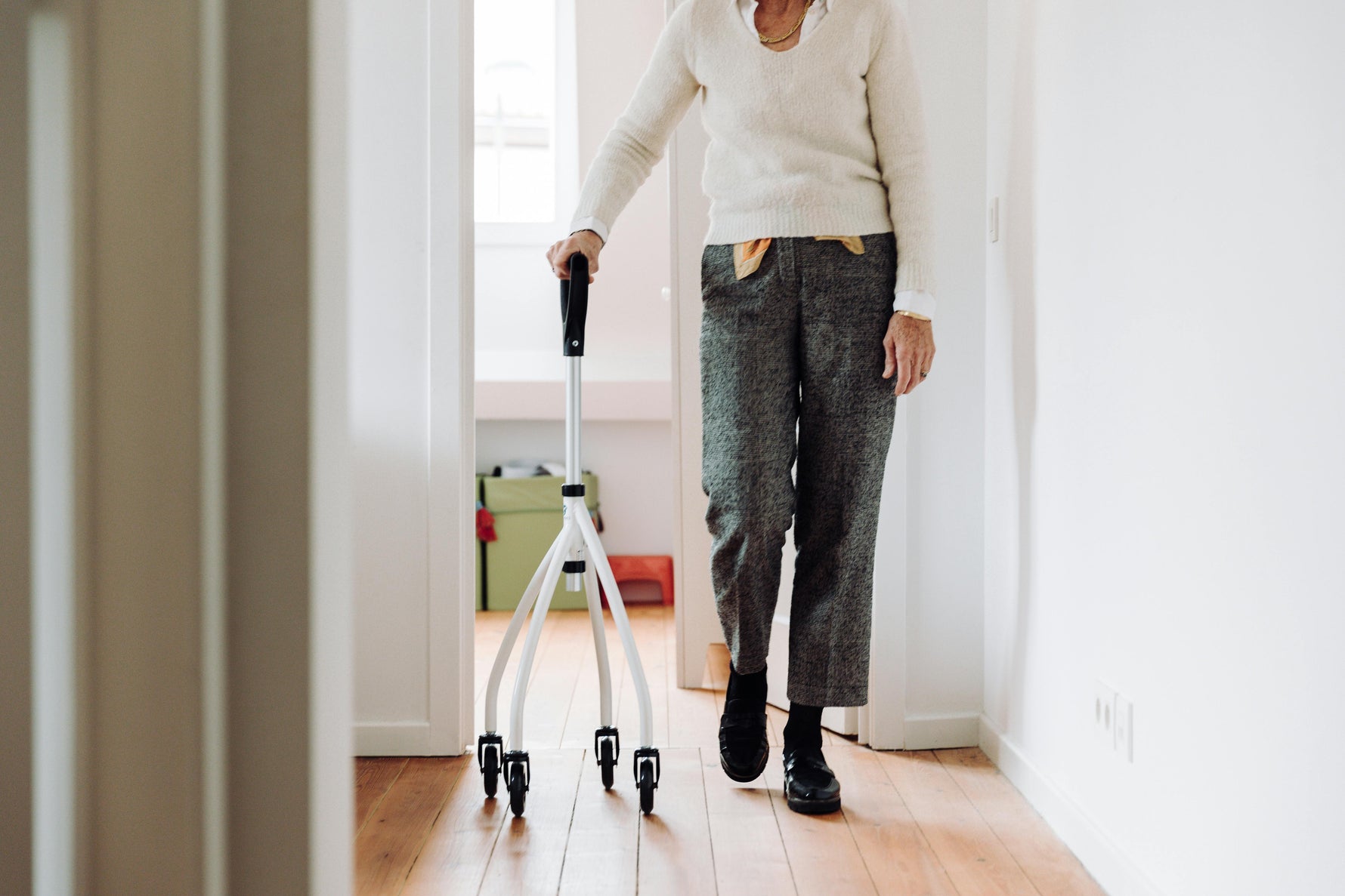 Senior using a 4-wheel walker for mobility support at home