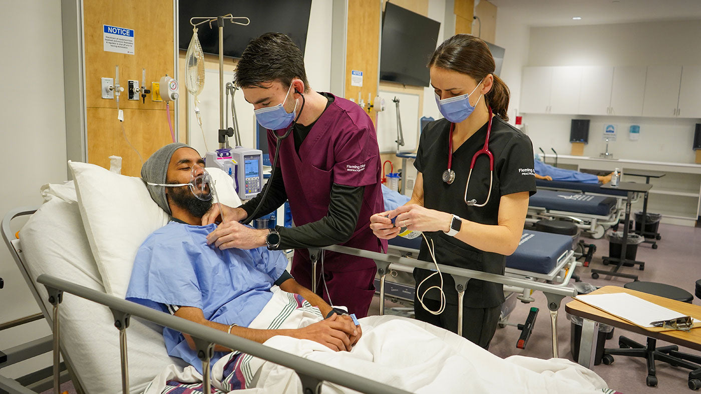 Respiratory therapist and nurse care for patient with oxygen mask in hospital bed