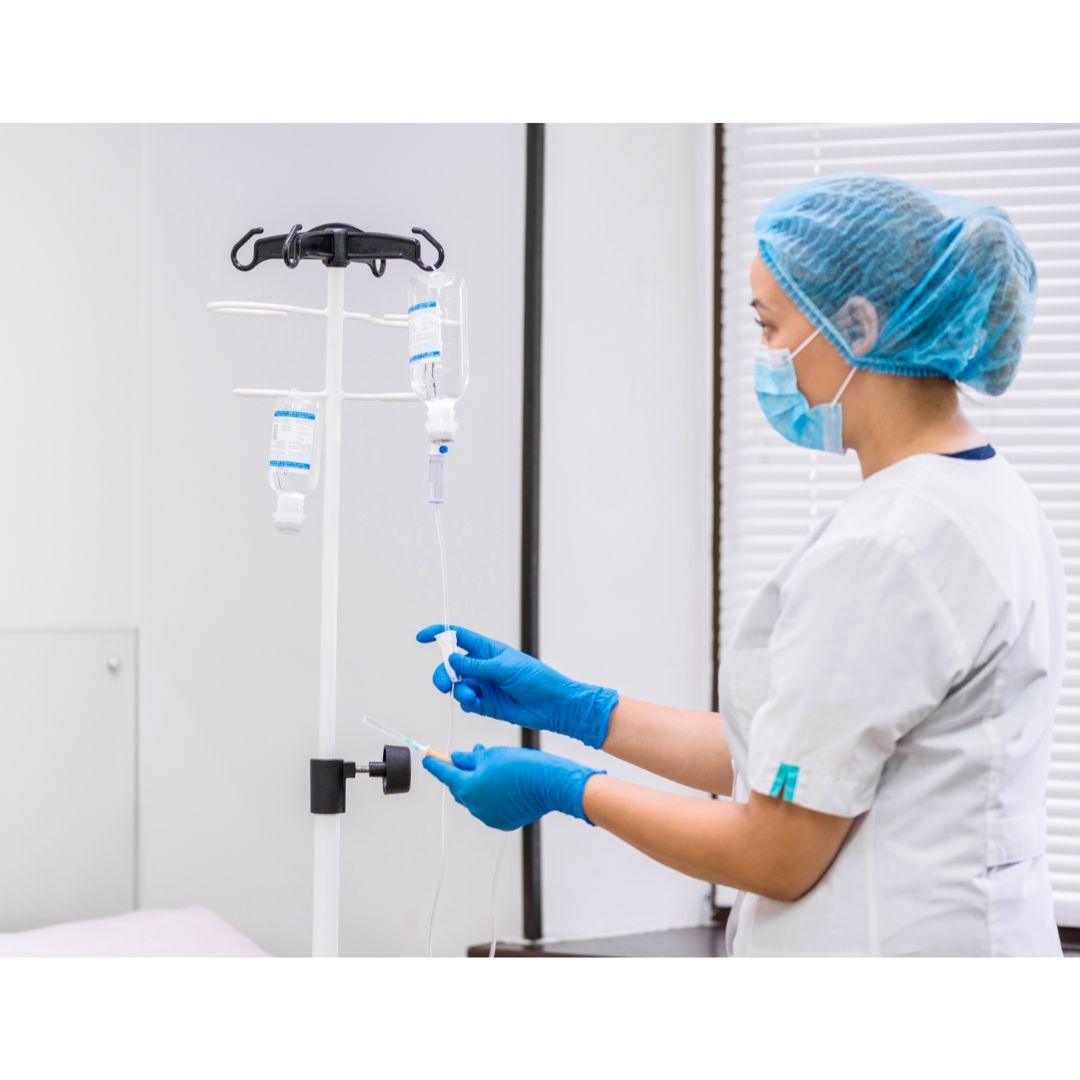 Nurse in medical attire preparing IV saline solution in a clinical setting