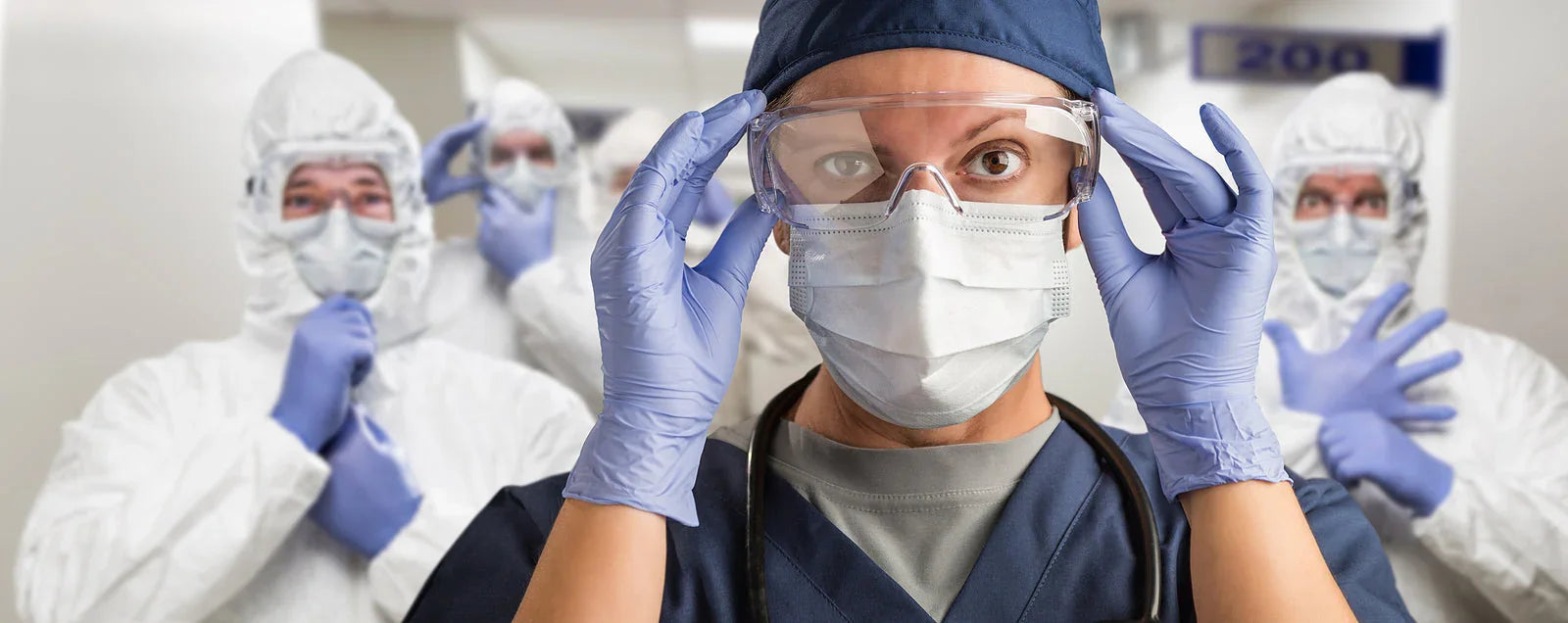 Doctors in PPE suits, face masks, goggles, and gloves in a medical facility corridor