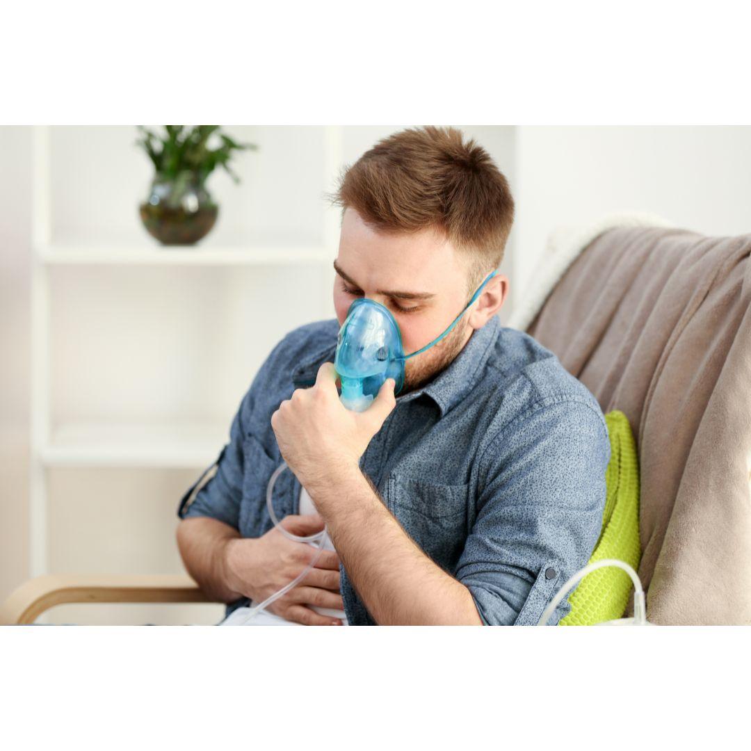 Man using home nebulizer machine for respiratory therapy on sofa