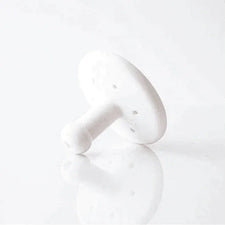 White plastic medical filter with perforated round disc on reflective surface
