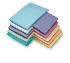 Stack of assorted colored disposable dental bibs on white background