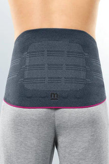 Person wearing a grey lumbar back support belt for pain relief and posture correction