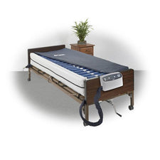 Hospital bed with adjustable air mattress, medical equipment, and wooden bedside table