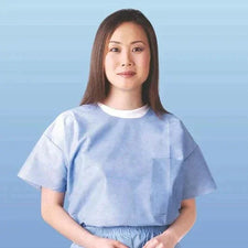 Woman wearing light blue disposable medical exam gown against gradient background