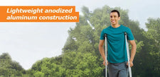 Smiling man outdoors using lightweight anodized aluminum crutches, mobility aid in nature.