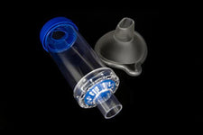 Clear plastic inhaler spacer with mask attachment for respiratory care against black background