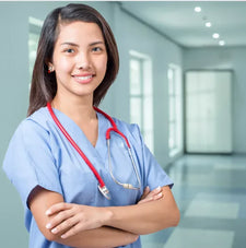 Smiling nurse in blue scrubs with stethoscope standing in bright medical facility